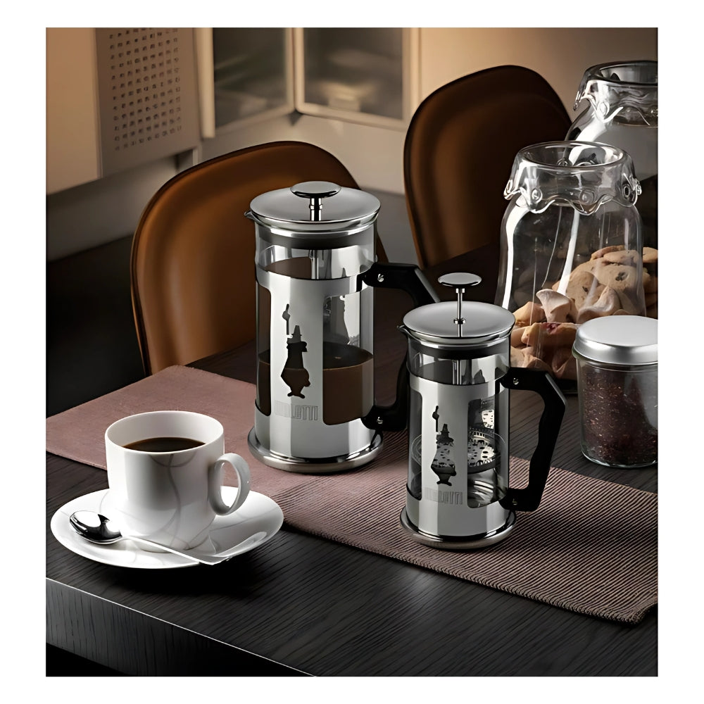 A Bialetti French Press 8-Cup Cafetiere made of stainless steel and aluminum, featuring a sleek design with a sturdy handle, ideal for brewing rich and aromatic coffee, on a table with a cup of Coffee. 